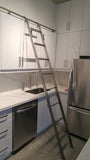 Modern white kitchen boasts custom built metal ladder and a 9ft long metal rail .  Ladder with multiple  hooks was specially designed so it can be used not only for the tall  cabinets  in the kitchen but also for the tall closet in the bedroom. Allowing  for maximum versatility on multiple rails and  when one wants to store it elsewhere.