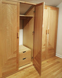 Custom storage solutions - Closet with solid oak wood doors, designed for a  room with ceiling at an angle.
