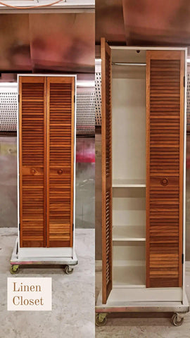 The vintage bi-fold louvered doors were converted into a laundry closet . The cabinet features a hanging rod and two adjustable shelves.