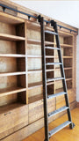 Mak​ing a big statement ​, the rough pine bookcase with a rolling ladder is almost 14 ft long  and has plenty of space for books and  display items,   Drawers were designed to hold files/folders as ​shelving is going in St​acie's beautiful ​home office  in her ​amazing farmhouse​.  ​To bring the old-time library and bookstore charm, a vintage orchard ladder was refurbished and retrofitted  with the black-finished iron hardware to add a contrast and a touch of industrial panache.