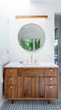 Wooden walnut  bathroom vanity with round mirror and white countertop