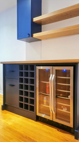By converting the hallway between the living and dining areas into a dry bar with a beverage center, gave this home added valuable counter space and enhanced storage with dedicated drawers for bar accessories and snacks.

The sleek white oak floating shelves add a touch of elegance and provide display space for bottles and glassware. Additionally, the white oak countertop creates a stunning contrast against the bold blue cabinetry.