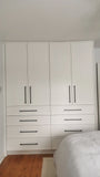 White wardrobe with black handles in a bedroom setting