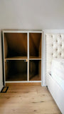 Custom-built angled cabinet designed for an unusual space under a sloped ceiling beside the bed, adding not only functional storage but also features a convenient pull-out nightstand.