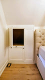 Custom-built angled cabinet designed for an unusual space under a sloped ceiling beside the bed, adding not only functional storage but also features a convenient pull-out nightstand.