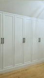 A closet design   specifically tailored to fit rooms with sloped or slanted ceilings, featuring beveled shaker doors. The design maximizes storage while creating both a functional and beautiful space.