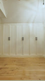 A closet design   specifically tailored to fit rooms with sloped or slanted ceilings, featuring beveled shaker doors. The design maximizes storage while creating both a functional and beautiful space.