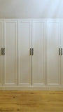 A closet design   specifically tailored to fit rooms with sloped or slanted ceilings, featuring beveled shaker doors. The design maximizes storage while creating both a functional and beautiful space.