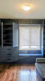 A custom floor-to-ceiling, wall-to-wall storage unit designed to frame a window. The design includes a spacious section featuring two doors and three drawers, perfect for keeping items out of sight. It also incorporates open shelving, which is ideal for displaying decor, books, bar essentials, or electronics. Additionally, the unit features a custom bench-cum-chest to provide both extra seating and integrated storage.