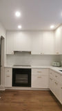 This kitchen, for instance, showcases a blend of beautiful and classic design. The upper cabinets feature a slim shaker panel design, while the base cabinets have a thin rail with rounded edges. Additionally, the kitchen includes a pantry discreetly tucked into an alcove with an arched opening, as well as panel-ready refrigerator and dishwasher. The peninsula island, complete with a sink and seating, is designed to be a central focal point.