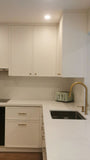 This kitchen, for instance, showcases a blend of beautiful and classic design. The upper cabinets feature a slim shaker panel design, while the base cabinets have a thin rail with rounded edges. Additionally, the kitchen includes a pantry discreetly tucked into an alcove with an arched opening, as well as panel-ready refrigerator and dishwasher. The peninsula island, complete with a sink and seating, is designed to be a central focal point.
