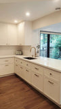 This kitchen, for instance, showcases a blend of beautiful and classic design. The upper cabinets feature a slim shaker panel design, while the base cabinets have a thin rail with rounded edges. Additionally, the kitchen includes a pantry discreetly tucked into an alcove with an arched opening, as well as panel-ready refrigerator and dishwasher. The peninsula island, complete with a sink and seating, is designed to be a central focal point.