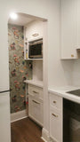 This kitchen, for instance, showcases a blend of beautiful and classic design. The upper cabinets feature a slim shaker panel design, while the base cabinets have a thin rail with rounded edges. Additionally, the kitchen includes a pantry discreetly tucked into an alcove with an arched opening, as well as panel-ready refrigerator and dishwasher. The peninsula island, complete with a sink and seating, is designed to be a central focal point.