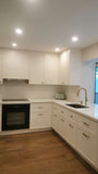 This kitchen, for instance, showcases a blend of beautiful and classic design. The upper cabinets feature a slim shaker panel design, while the base cabinets have a thin rail with rounded edges. Additionally, the kitchen includes a pantry discreetly tucked into an alcove with an arched opening, as well as panel-ready refrigerator and dishwasher. The peninsula island, complete with a sink and seating, is designed to be a central focal point.