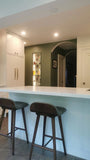 This kitchen, for instance, showcases a blend of beautiful and classic design. The upper cabinets feature a slim shaker panel design, while the base cabinets have a thin rail with rounded edges. Additionally, the kitchen includes a pantry discreetly tucked into an alcove with an arched opening, as well as panel-ready refrigerator and dishwasher. The peninsula island, complete with a sink and seating, is designed to be a central focal point.