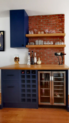 Modern kitchen bar with wooden counter, blue cabinets, and brick wall.