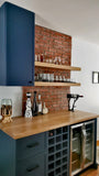 Modern kitchen with wooden shelves, blue cabinets, and a brick wall.
