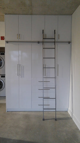 Modern white closet boasts custom built metal ladder and a 7ft long metal rail .  Ladder with multiple hooks was specially designed so it can be used not only for the tall  closet in the bedroom but also in the kitchen. Allowing  for maximum versatility on multiple rails and to store it elsewhere.