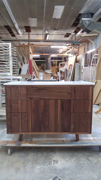   This 48" gorgeous MCM  inspired vanity features solid wood frame, legs and door & drawer fronts built from  walnut with exceptional grain pattern throughout.  Modern lines and beautiful  & warm wood grains makes it a perfect statement in any contemporary bathroom.  Two precisely inset doors and six functional drawers with soft-close slides offer plenty of storage for a growing family.  The counter top is a low maintenance and durable single edge white quartz  with an under-mount ceramic sink.