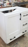 Shown in the photos is a 30" wide custom floating vanity designed to accommodate a off centered sink.  Cabinet built  from solid poplar wood.  Shaker style fronts.  Soft close drawers and doors.  Painted white.   30" W x  20" D x  29" (ht)