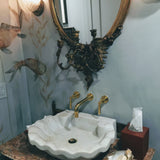 Amazing shell shaped marble sink from Inde-Art paired with an antique mirror & gold faucet gives  designer Michelle Hanna's bathroom a luxurious grand Parisian style.