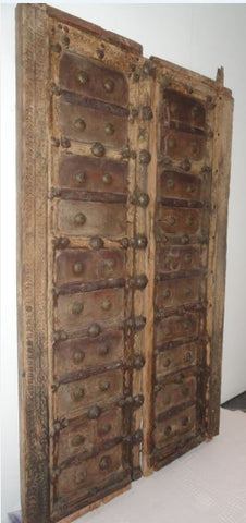 Rajasthani antique wooden doors with iron fittings and details.  The doors are rustic, weather beaten with great patina & heavy.  Can be hanged on the wall as a feature display or used as functional door panels  Approximately 17”wide x 80” high / each