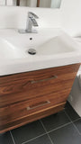 A bland IKEA bathroom vanity was transformed into an elegant modern cabinet by replacing existing fronts with beautiful warm solid walnut drawer fronts. Also to customized storage space 3 drawer unit was turned into 2 drawer instead, to accommodate taller items.