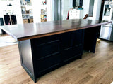 This amazing island with solid maple wood counter top not only adds storage to this kitchen and space for a wine cooler but with over hang on all four sides also acts  like a table for big family gatherings.  The black cabinetry  serves as a clean slate for beautiful solid maple wood counter top A playful balance of casual and sophisticated.