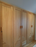 Custom storage solutions - Closet with solid oak wood doors, designed for a  room with ceiling at an angle.