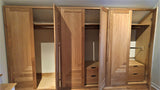 Custom storage solutions - Closet with solid oak wood doors, designed for a  room with ceiling at an angle.