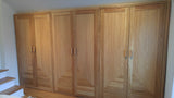 Custom storage solutions - Closet with solid oak wood doors, designed for a  room with ceiling at an angle.