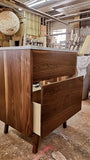 Custom build MCM inspired 30" solid walnut wood vanity​ cabinet​, featuring one deep soft close inset drawer ​, tapered wood legs, quartz countertop  with gray veins and a ceramic sink. 