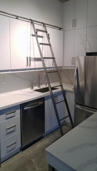 Modern white kitchen boasts custom built metal ladder and a 9ft long metal rail . Ladder with multiple hooks was specially designed so it can be used not only for the tall cabinets in the kitchen but also for the tall closet in the bedroom. Allowing for maximum versatility on multiple rails and when one wants to store it elsewhere.